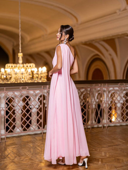 Woman in a pink dress standing in an elegant indoor setting with chandeliers.