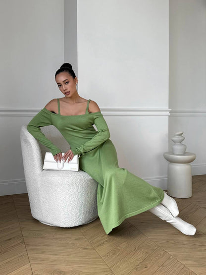 Woman in a green dress sitting on a white chair in a room with wooden flooring.