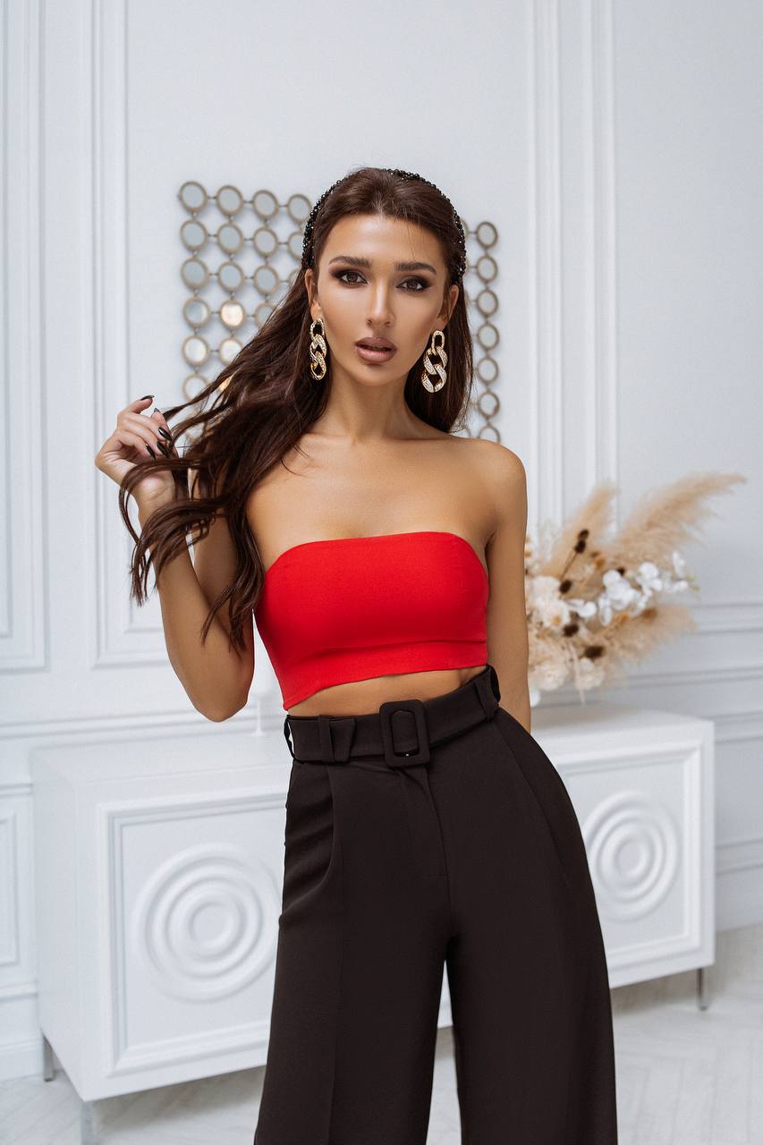 Woman wearing a red top and black pants in an elegant interior setting