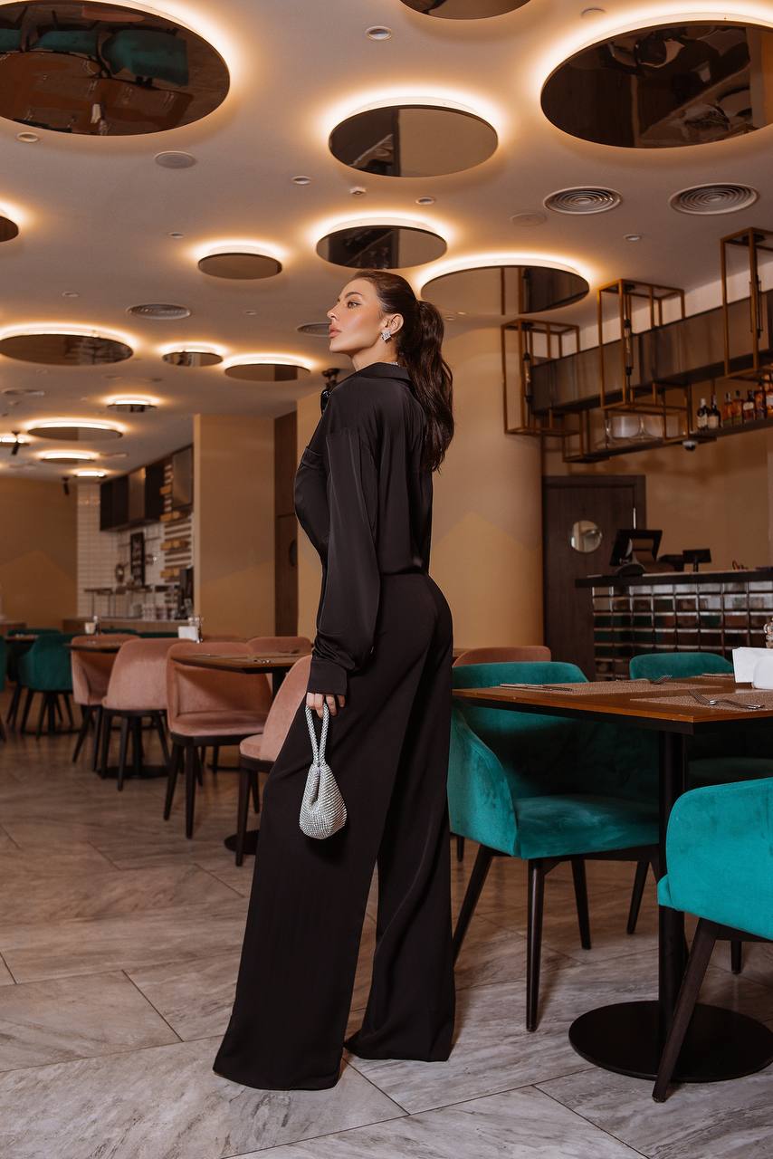 Woman in a black outfit standing in a modern restaurant with stylish interior design.