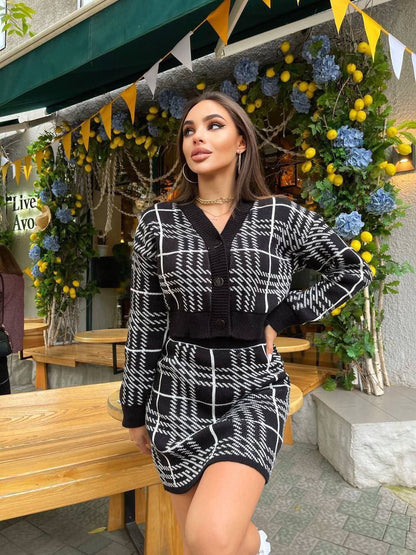 Woman in a black and white checkered outfit standing in front of decorative plants and flowers.