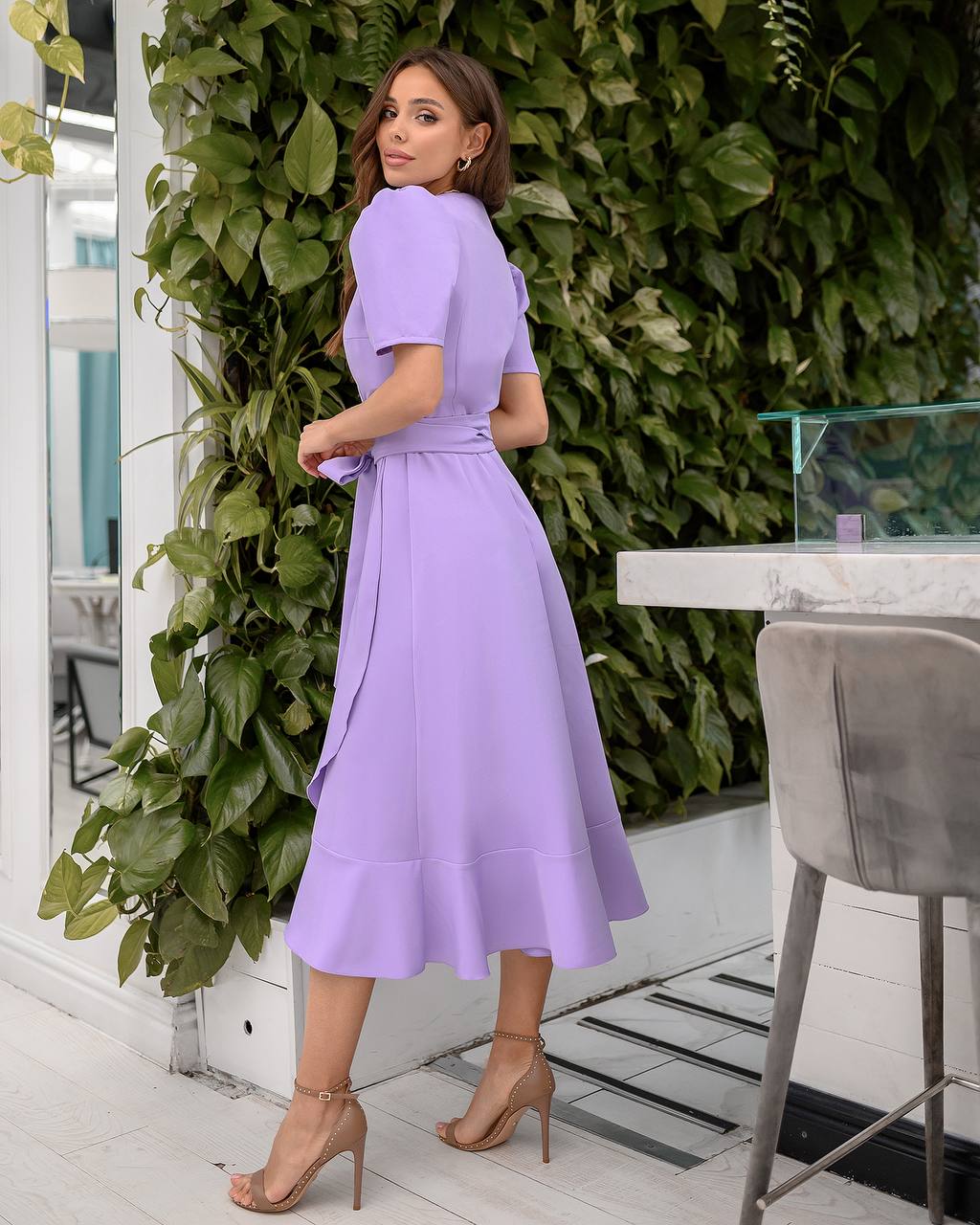 Woman in a purple dress standing in front of green foliage