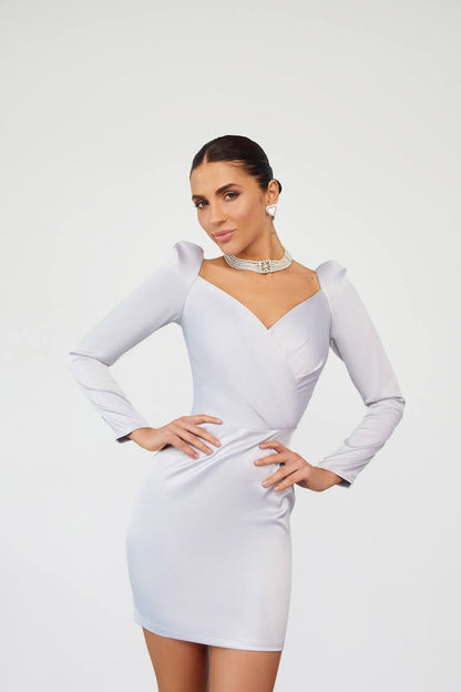 Woman wearing a white dress with long sleeves on a plain background