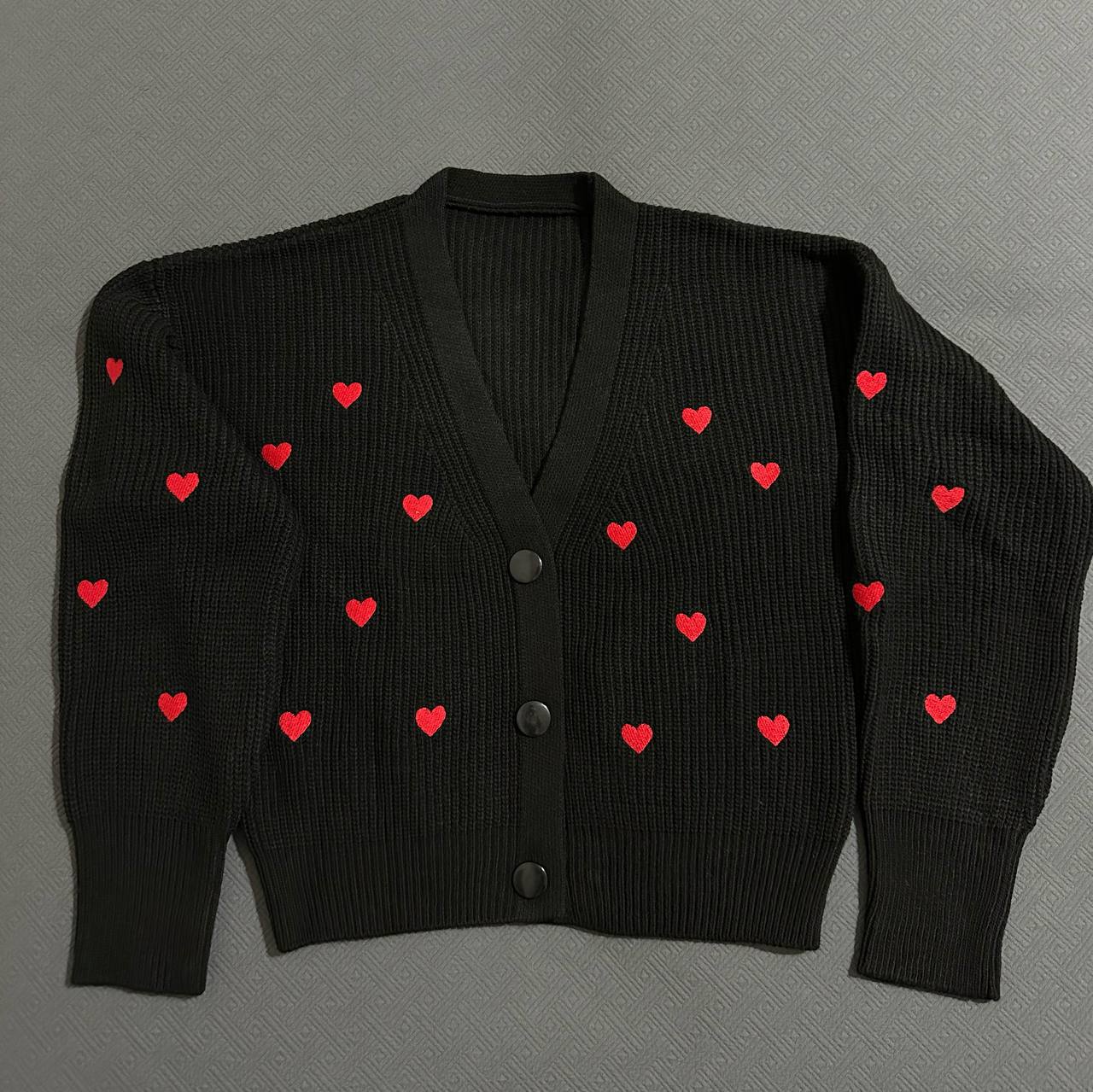 Black cardigan with red heart patterns on a gray background