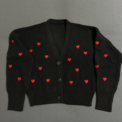 Black cardigan with red heart patterns on a gray background