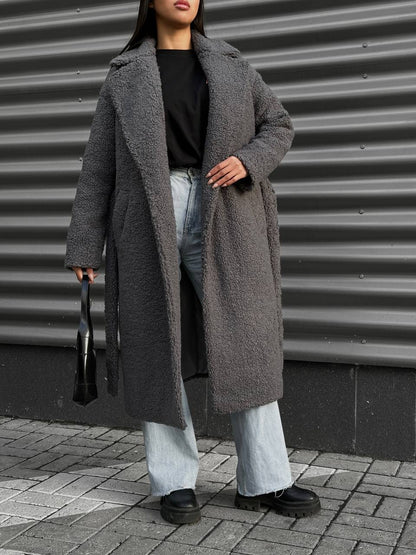 Person wearing a long gray coat with a neutral background