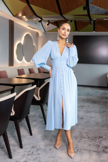 Woman in a light blue dress standing in a modern restaurant setting