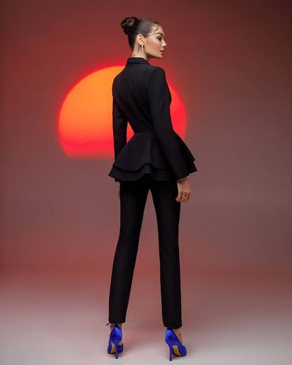 Woman in a black suit with peplum top against a red sun backdrop
