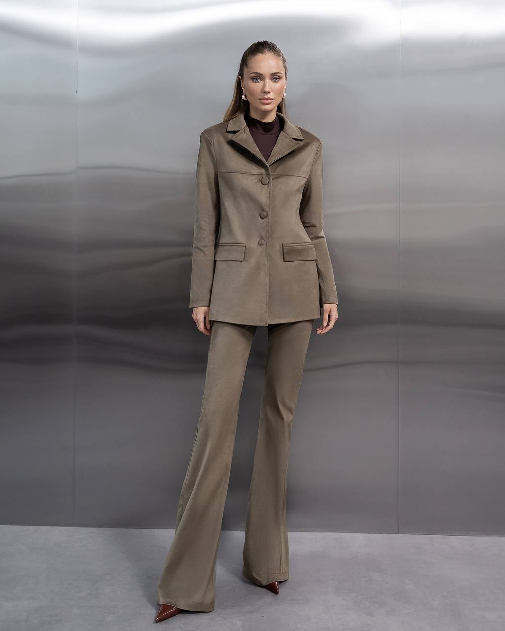 Woman wearing a beige suit against a plain background