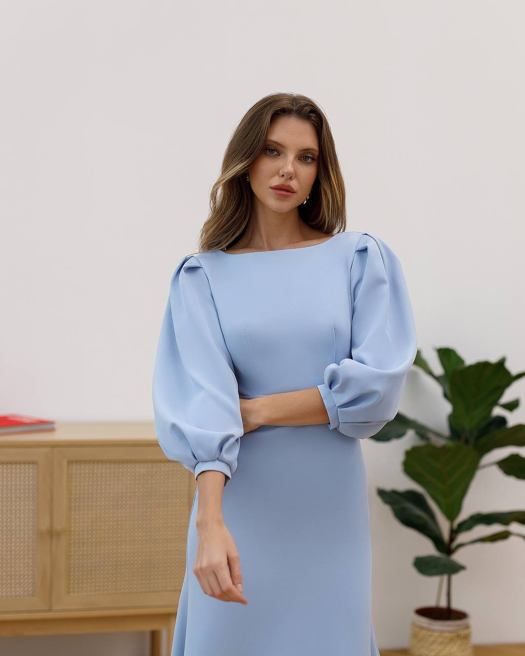 Woman wearing a light blue dress with puffed sleeves in an indoor setting.