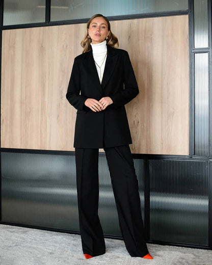 Woman in a black suit standing in an office setting