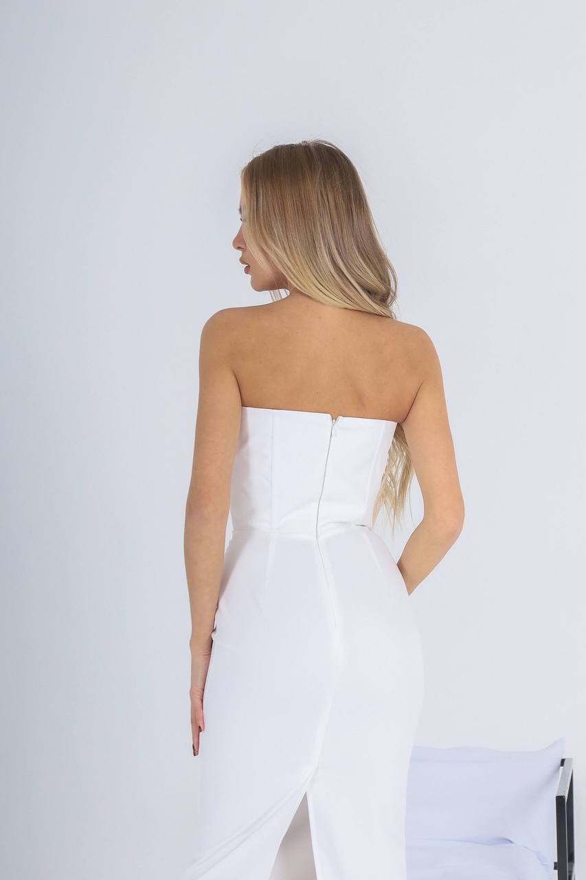 Woman wearing a strapless white dress against a plain background