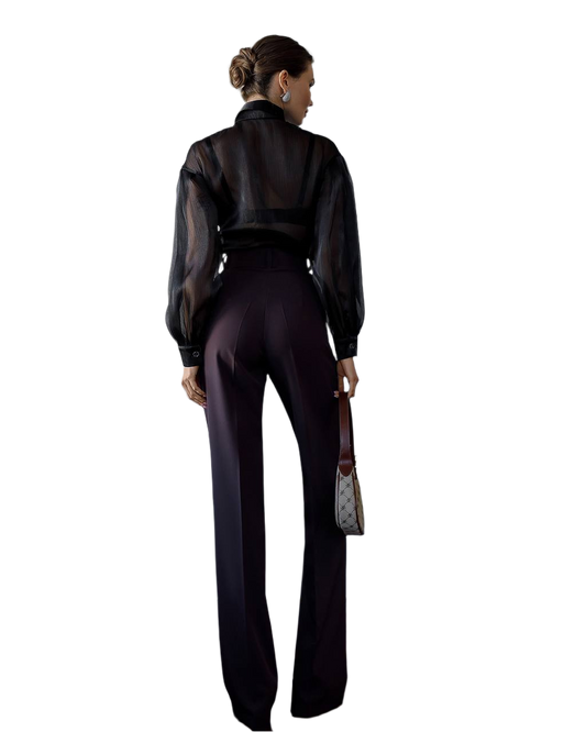 Person wearing a black outfit with sheer sleeves on a white background