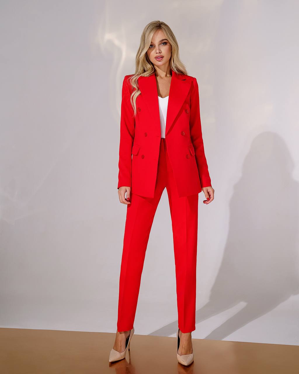 Woman wearing a red suit standing against a plain background