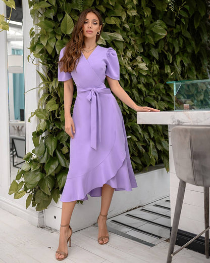 Woman in a purple dress standing in front of greenery