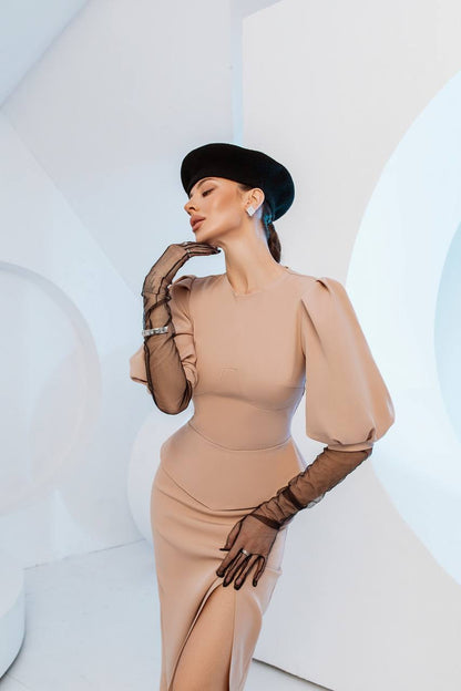 Woman in a beige dress and black hat posing against a white abstract background