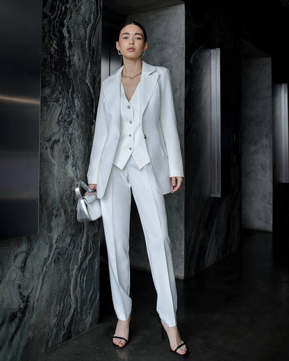 Woman in a light gray suit standing in a dark room with marble walls.