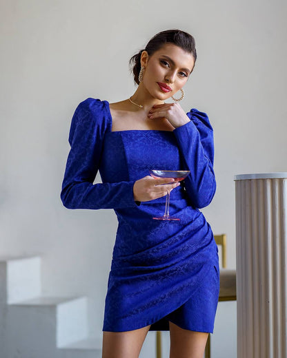 Woman in a blue dress holding a glass in an indoor setting