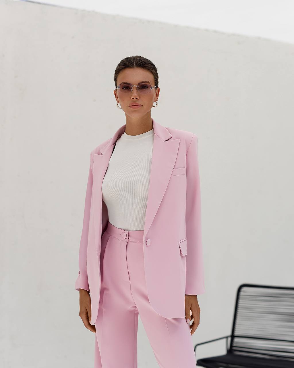 Person wearing a pink suit with a white top against a plain background