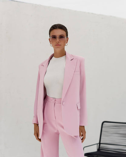 Person wearing a pink suit with a white top against a plain background
