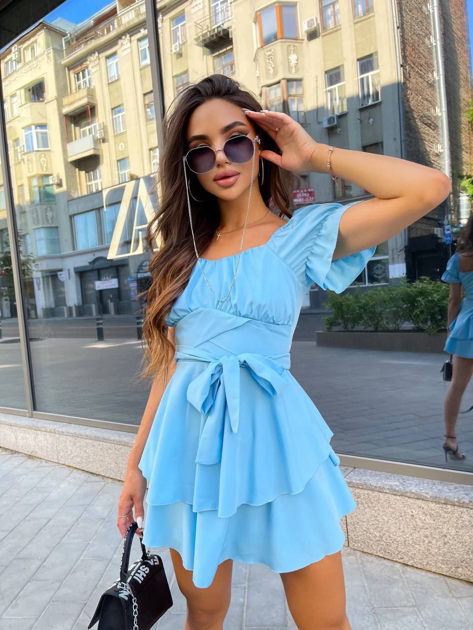 Woman in a light blue dress with sunglasses in an urban setting