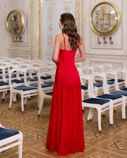 Woman in a red dress standing in an elegant room with white chairs and gold decorations.