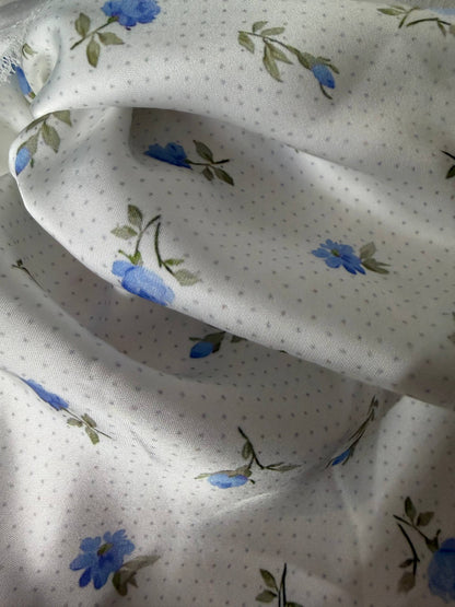 Floral patterned fabric with blue flowers and green leaves on a white background