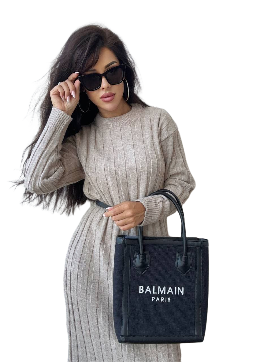 Woman holding a Balmain handbag against a white background