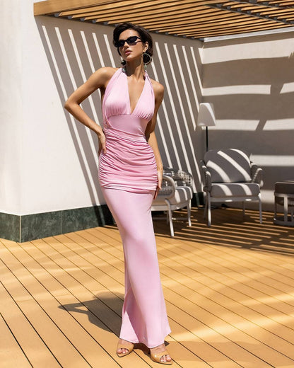Woman in a pink dress standing on a wooden deck with striped shadows.