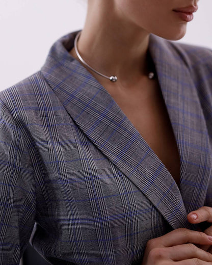Close-up of a person wearing a gray checkered blazer with a necklace.