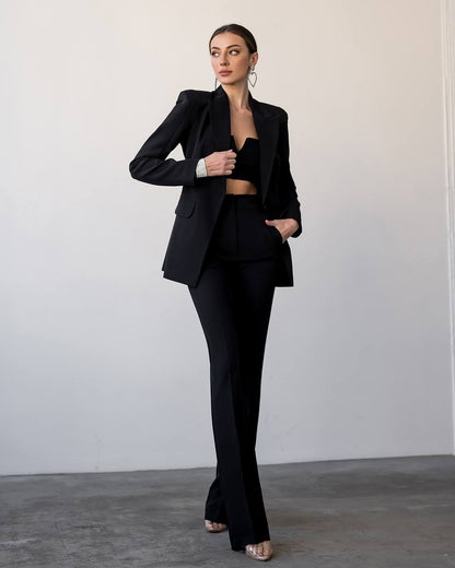 Woman wearing a black suit against a plain background