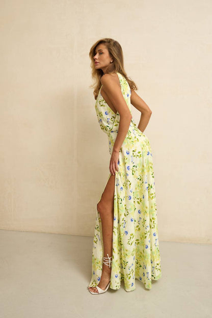 Woman wearing a yellow floral dress with a slit on a beige background