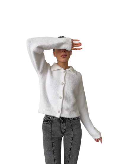 Person wearing a white cardigan and gray pants on a white background