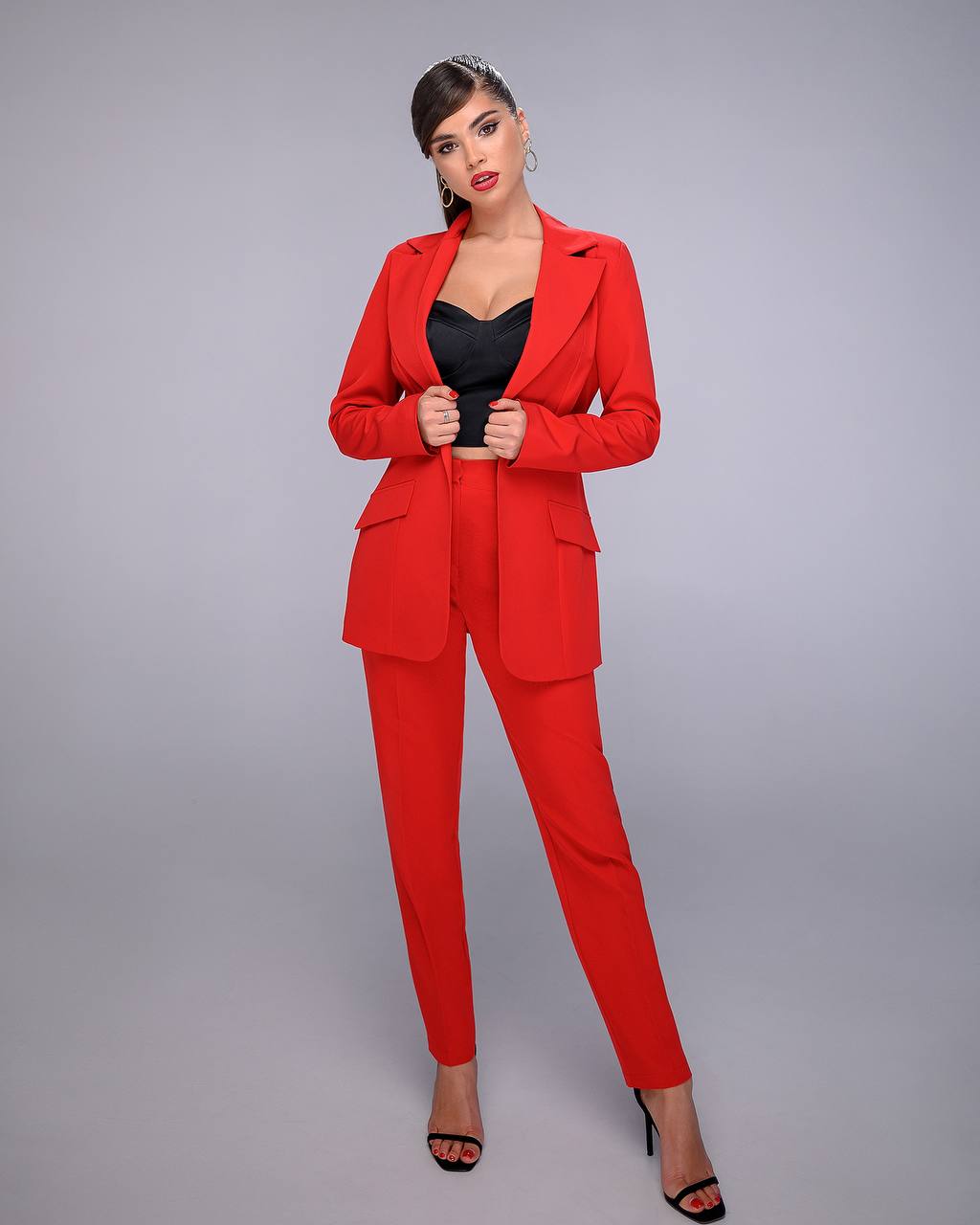 Woman wearing a red suit with a black top on a gray background