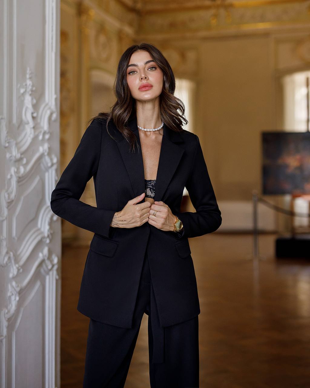 Woman in a black suit standing in an elegant interior setting