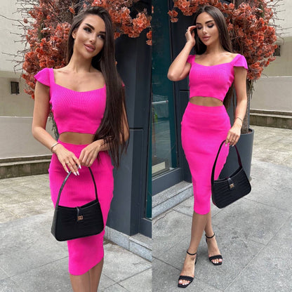 Woman in a bright pink outfit with a black handbag standing outdoors.