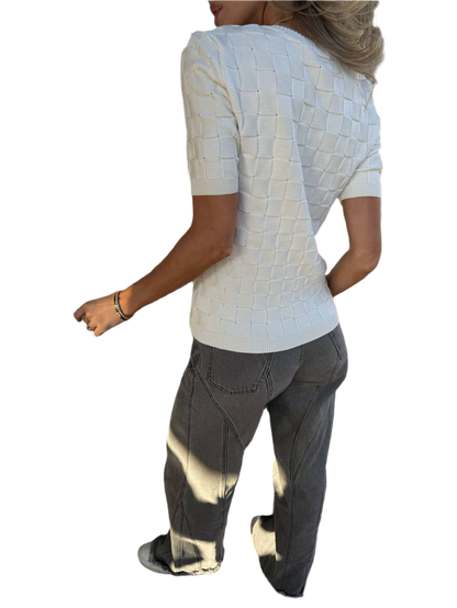 Person wearing a textured white top and dark pants on a white background