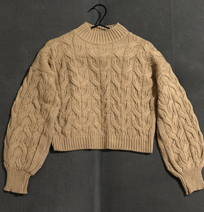 Beige cable knit sweater on a dark background