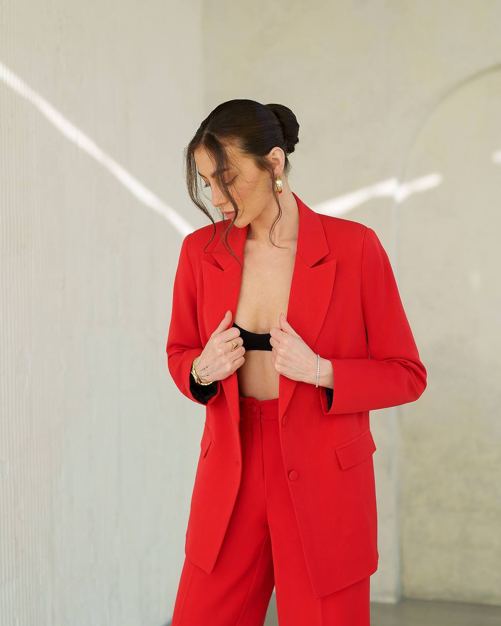 Person wearing a red suit with a black top underneath against a neutral background