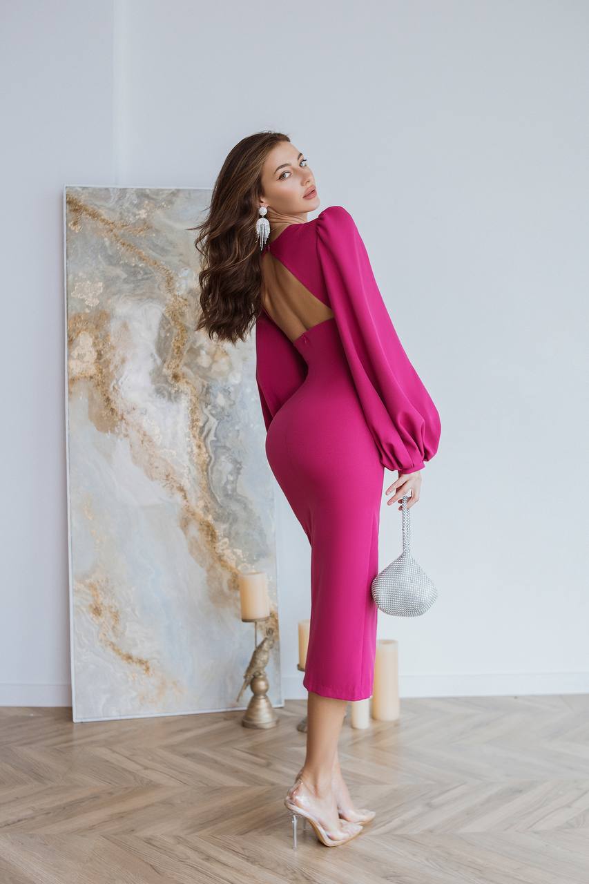 Woman in a pink dress standing in a room with a marble wall.