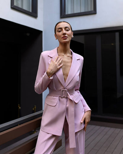 Woman wearing a pink suit standing in an outdoor setting.