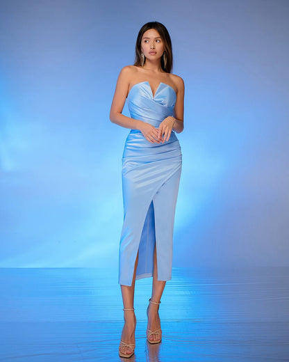 Woman wearing a strapless blue dress with a slit on a blue background