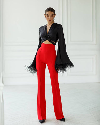 Woman wearing a black top and red pants against a white background