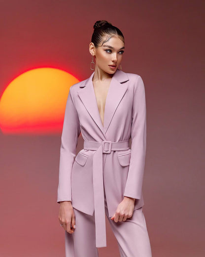 Woman in a pink suit standing against a sunset background