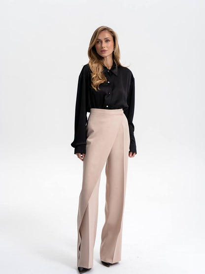 Woman wearing a black blouse and beige pants on a white background