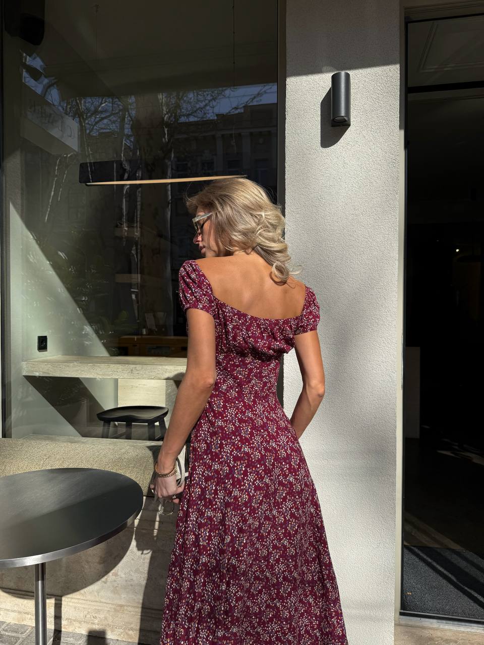 Woman in a red floral dress standing in a modern indoor setting.
