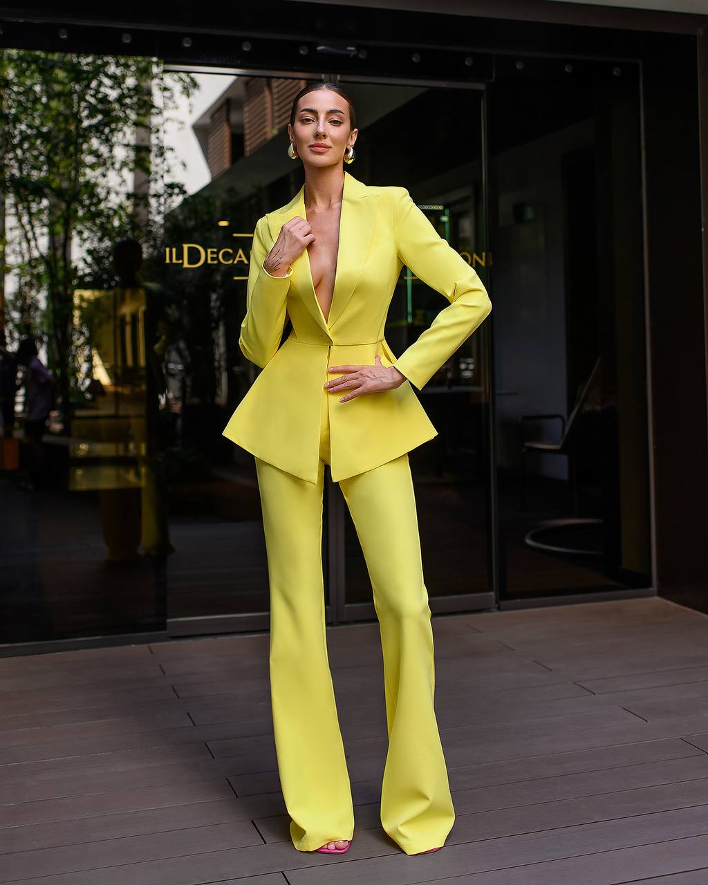 Woman in a bright yellow suit standing in front of a building entrance.
