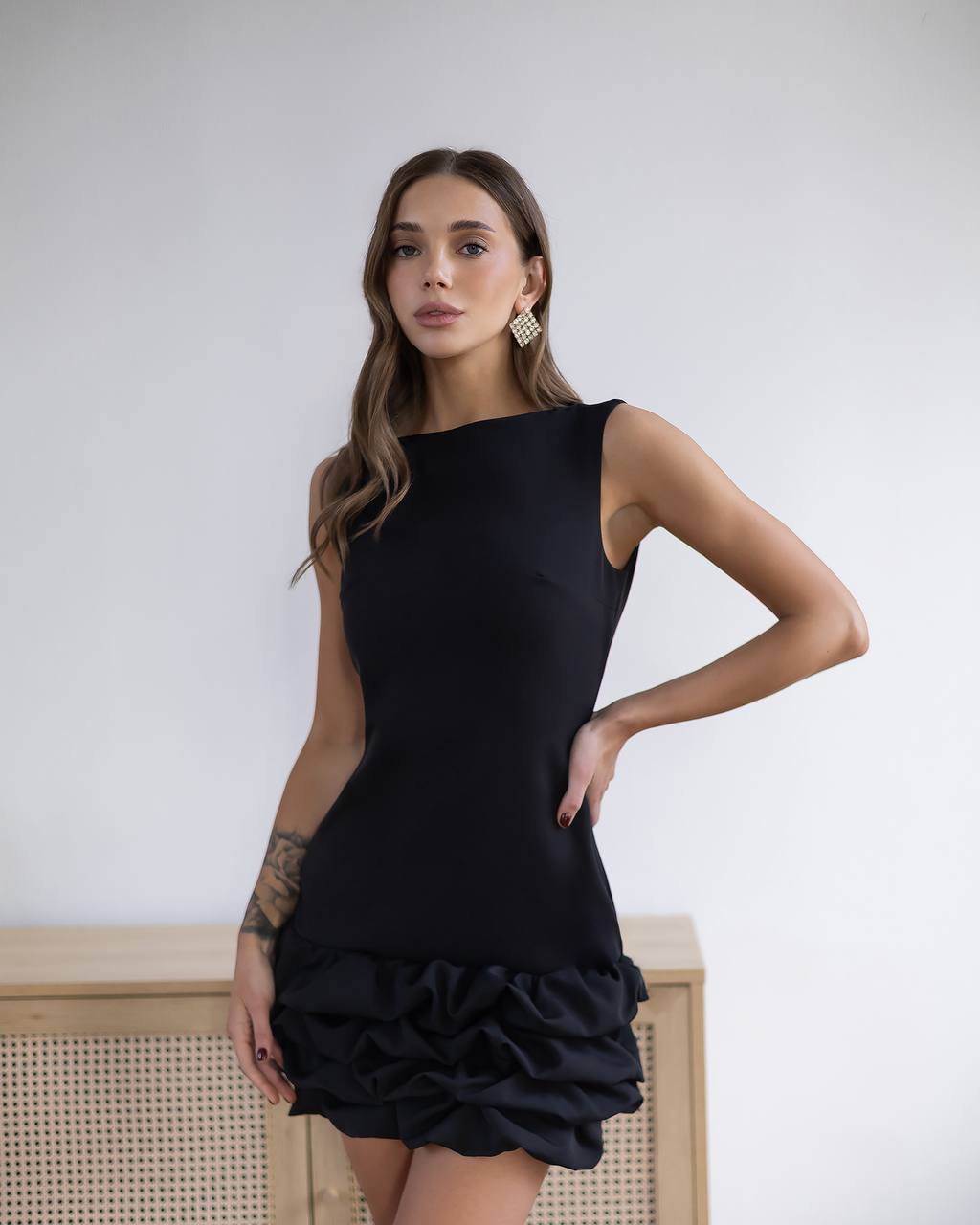 Woman wearing a black dress with ruffled bottom half against a white background