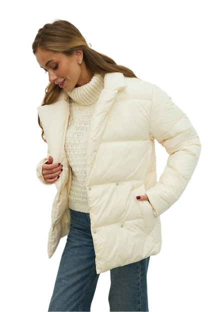 Woman wearing a cream puffer jacket over a knitted sweater on a white background