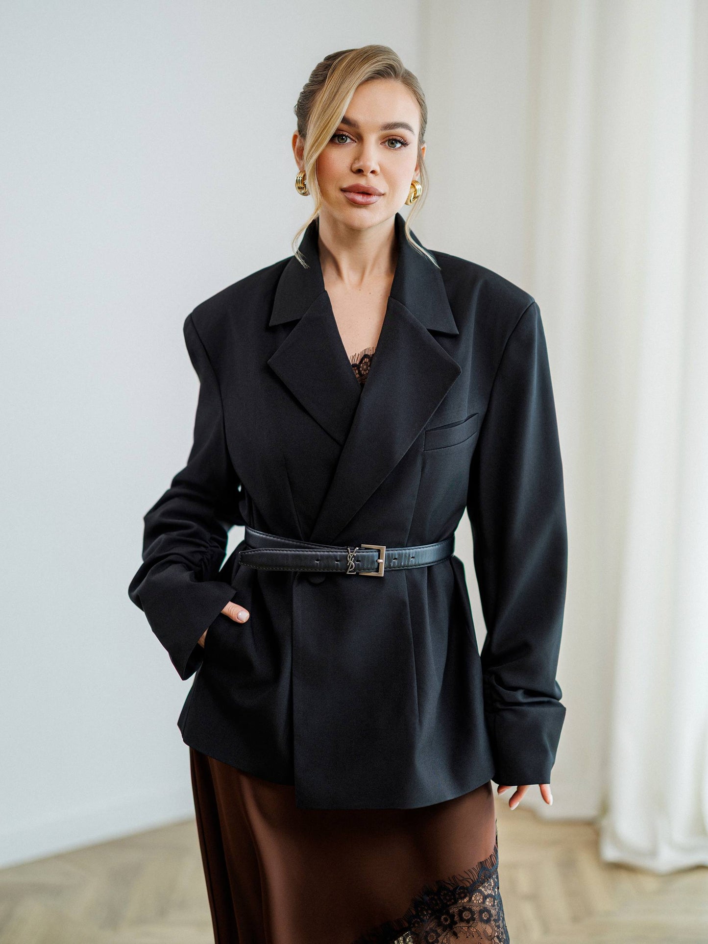 Woman wearing a black coat with a belt in an indoor setting